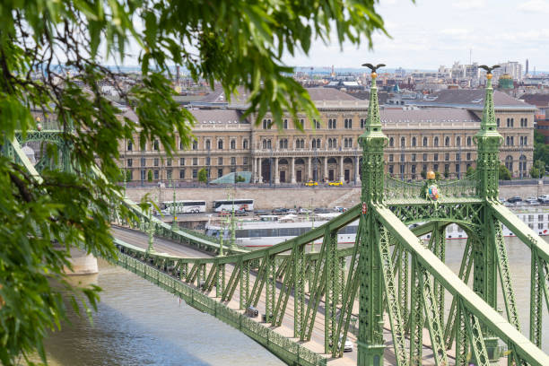ドナウ川に架かるリバティ橋またはフリーダム橋。コルヴィヌス大学が背景にあります。ブダペスト, ハンガリー - corvinus university ストックフォトと画像
