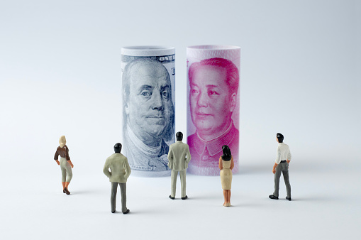 Businessman/Politician figurines scrutinize the US dollar and Chinese Yuan