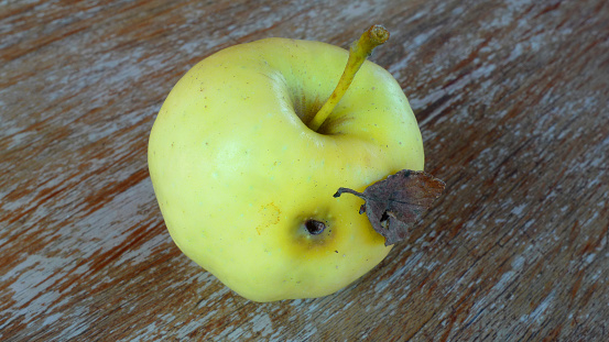 Organic, healthy, chemically-free yellow rotten apple on a wooden table