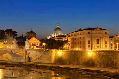 A nighttime view of the Dome of St. Peter's Basilica across the Tiber River in Rome taken from St Angelo's Bridge (Ponte Sant'Angelo).