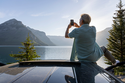 He takes smart phone pic of view. Lake Minnewanka, Banff NP, Alberta
