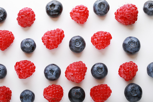 pattern of fresh blueberries and raspberries on a white background, food concept