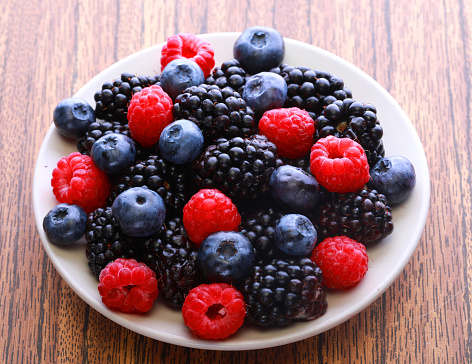 Blackberries, raspberry and blueberrys on white plate. Close up.