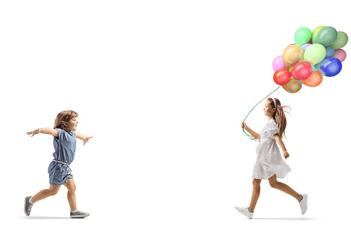 Girl with balloons running towards a little girl isolated on white background