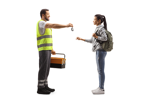 Full length profile shot of a road assistance agent giving car keys to a female student isolated on white background