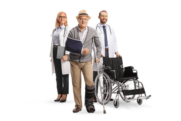 full length portrait of a senior patient with crutches and doctors in the back - physical injury men orthopedic equipment isolated on white imagens e fotografias de stock
