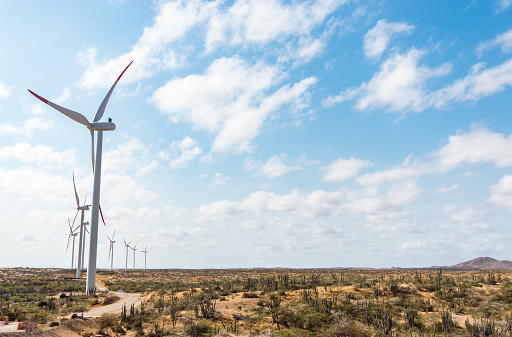 Awe-inspiring view of a wind farm standing tall amidst the vastness of the Guajira Desert, harnessing the power of the sun and wind on a sunny day
