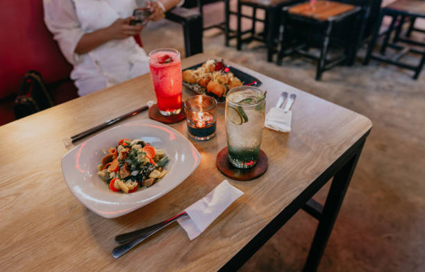 Dish of capcay and cheese fried banana dinner with fresh drink of apple breeze and strawberry breeze by candlelight on wooden table.