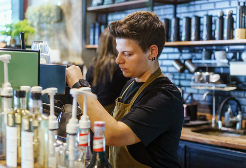 Young female barista preparing cappuccino in a coffee shop