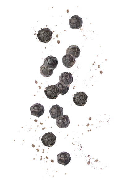 Ground black pepper (peppercorn) falling isolated on white
