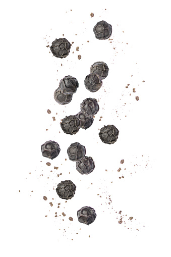 Ground black pepper (peppercorn) falling isolated on white background