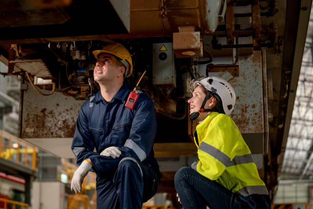 istock Technician man and train factory worker woman check and fix the problem and stay under electric train in maintenance center. 1499345079