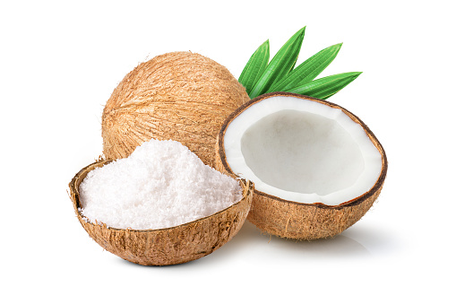 Coconut powder (shredded coconut, coconut flour) and brown coconut with green leaf isolated on white background.
