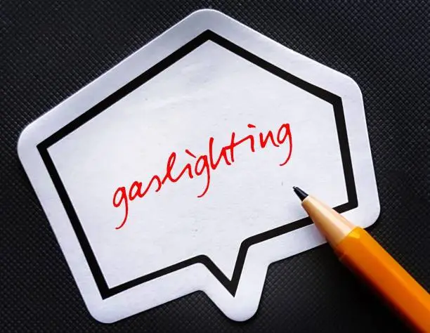 Note paper with handwriting text GASLIGHTING, refer to person who presents a false narrative to another which leads them to doubt their perceptions and become distressed and dependent on the gaslighter
