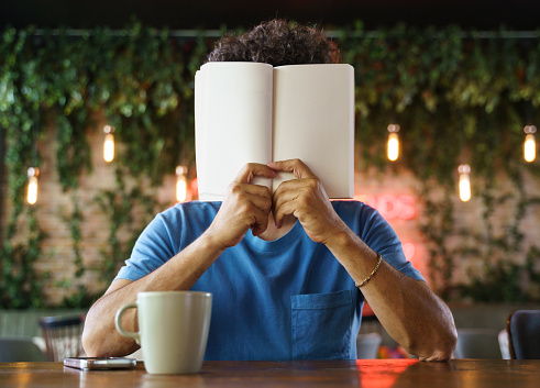 Portrait of a mid adult man holding an open book to his face