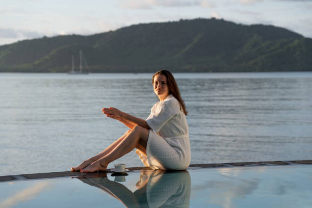 istock brunette girl in white bathrobe sits at edge of pool 1499366608