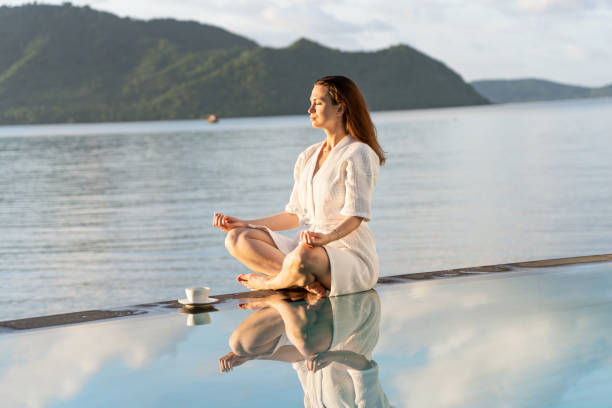 istock brunette in white robe sits at edge of pool, holding coffee mug 1499366670