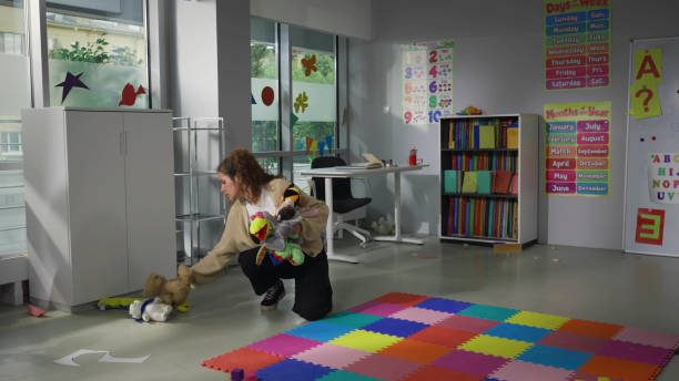 Tired young teacher clean playroom in kindergarten in evening Tired young teacher clean playroom in kindergarten in evening. Female teacher collect toys from floor at nursery school classroom preschool classroom jobs stock pictures, royalty-free photos & images