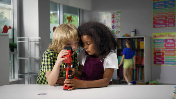 istock Boy and girl looking through microscope in playroom in kindergarten 1499373581