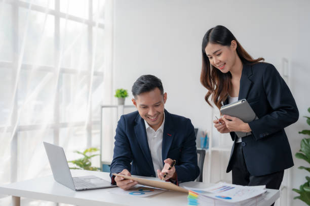 istock Two Young Asian business people discuss with new startup project Idea presentation, analyze planning and financial statistics and investment market at office. 1499376904