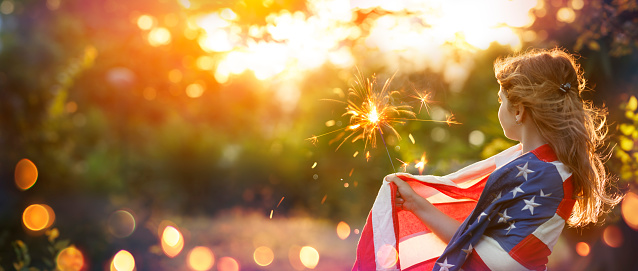 Independence Day - Little Girl With Usa Flag - Proud And Freedom Concept - Patriot With American Flag In Defocused Abstract Sunset