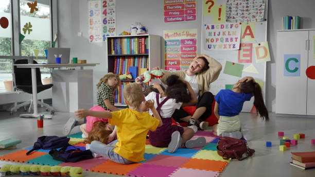 istock Group of elementary students exercising with teacher sitting on floor in classroom 1499379276