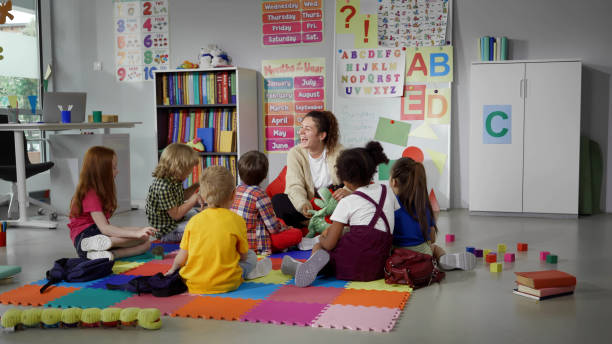 istock children sitting on floor while caring teacher explains lesson using toy in kindergarten 1499379405