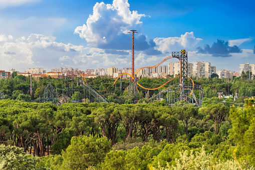 Madrid, Spain, May 27, 2023: Roller coaster of the amusement park of Madrid peeking over the vegetation of the Casa de Campo