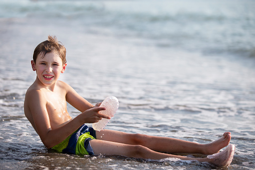 A teenage boy is sitting on the seashore.