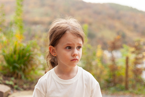 Portrait of a little girl in a white T-shirt outdoors