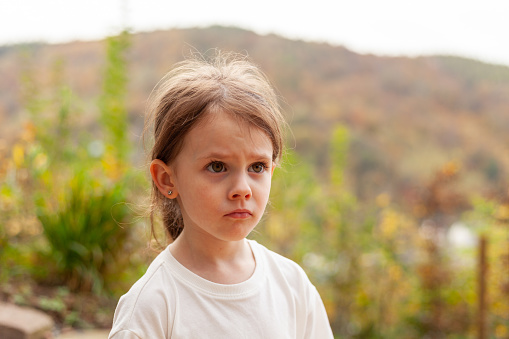 Little girl in a white T-shirt on a background of autumn nature