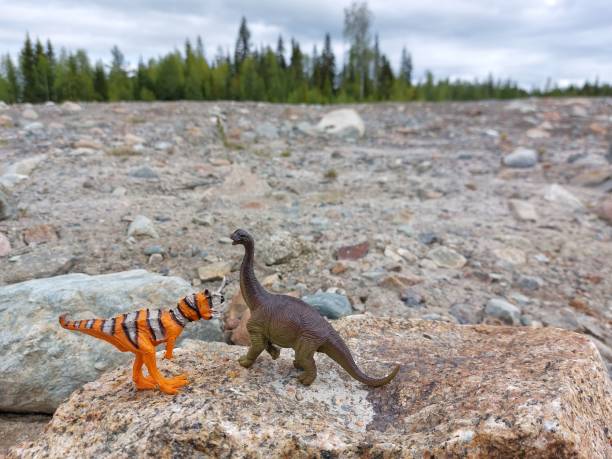 istock Two toy dinosaurs on rocks and debris 1499385049