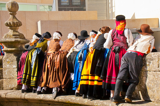 Lugo, Spain- October 10, 2010: Rear view of group of young people dressed up with multicolored folk traditional clothing in old town Lugo city, Galicia, Spain during San Froilán traditional celebrations.