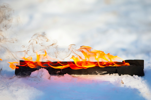Burning log in the snow. Fire on a wooden stick.