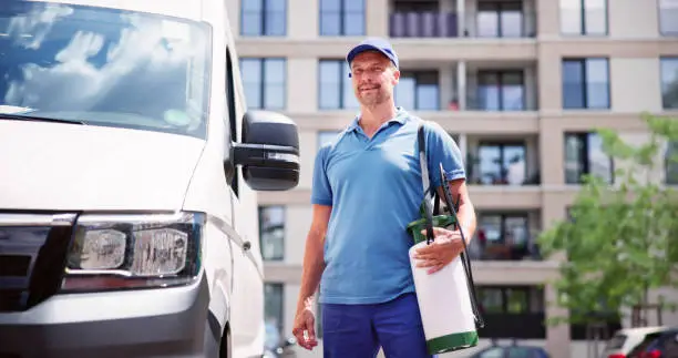 Confident Pest Control Worker Wearing Cap Against Truck