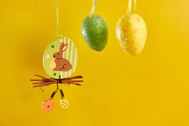 istock Easter beauty with a hanging rabbit and eggs on a yellow background. Easter celebration. 1499395628