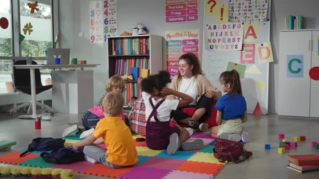 Group of elementary students exercising with teacher sitting on floor in classroom