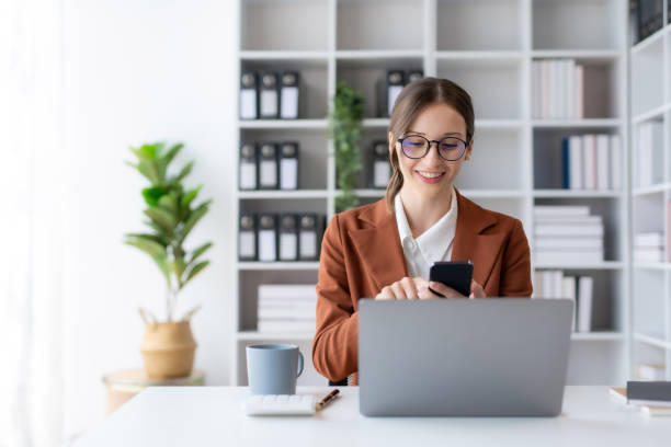 istock Beautiful smiling businesswoman using a smartphone to work on various application including mobile transaction to send messages, LINE, and various business information sent via social media. 1499400748