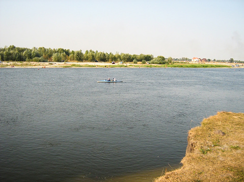 A double kayak with people floats down the river. Active recreation and leisure on the water. View from a distance, unidentified persons