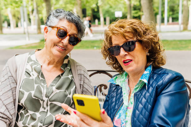 istock Aged women using mobile phone sitting on a park 1499402264