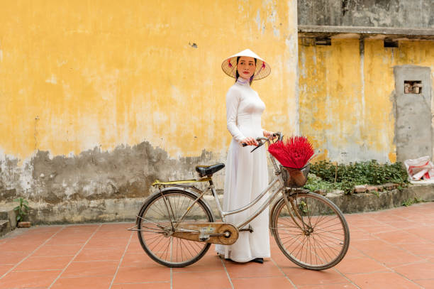 Happy Vietnamese girl in traditional white ao dai dress with vietnamese hat stock photo