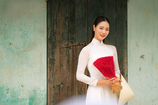 Happy Vietnamese girl in traditional white ao dai dress with vietnamese hat stock photo