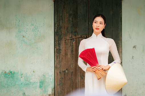 Happy Vietnamese girl in traditional white ao dai dress with vietnamese hat