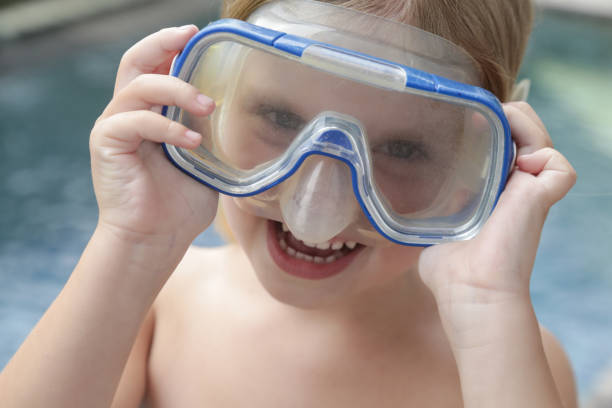 adorable niña alegre de 5 años con máscara de snorkel posando junto a la piscina - eyewear child glasses 6 7 years fotografías e imágenes de stock