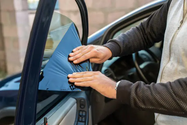 Photo of A man removes the tint from the side windows