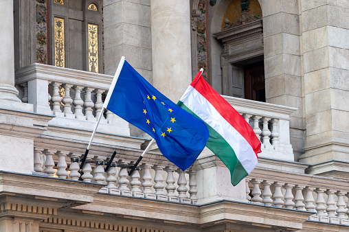 Flags of the European Union and Hungary flying from poles outside an ornate building in the centre of Hungarian capital city of Budapest