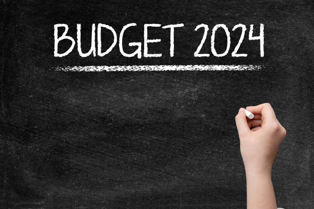 Budget 2024 on blackboard with woman hand