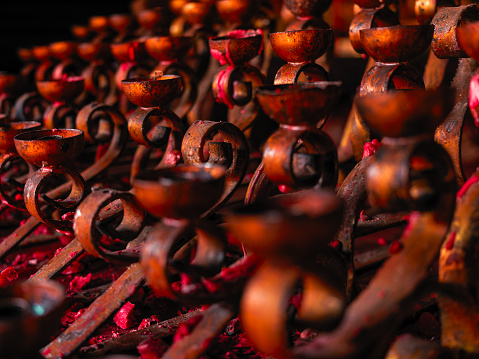 Empty candle holders covered in red wax at the Chinese temple in Indonesia
