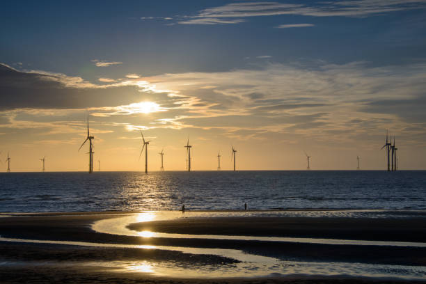 Fans of wind turbines spin over the sparkling sea. Dynamic clouds at sunset. Fans of wind turbines spin over the sparkling sea. Dynamic clouds at sunset. An offshore wind farm off the northwest coast of Taiwan. One of green power. offshore wind farm stock pictures, royalty-free photos & images