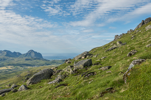 View from the summit of Justadtinden mountain overviewing the surrounding fjords and mountains. Hiking during summer on Lofoten islands in Norway.